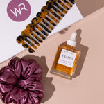flat lay of hair oil, tortoise shell comb and satin scrunchie