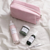 skincare products laid in front of a pink corded bag