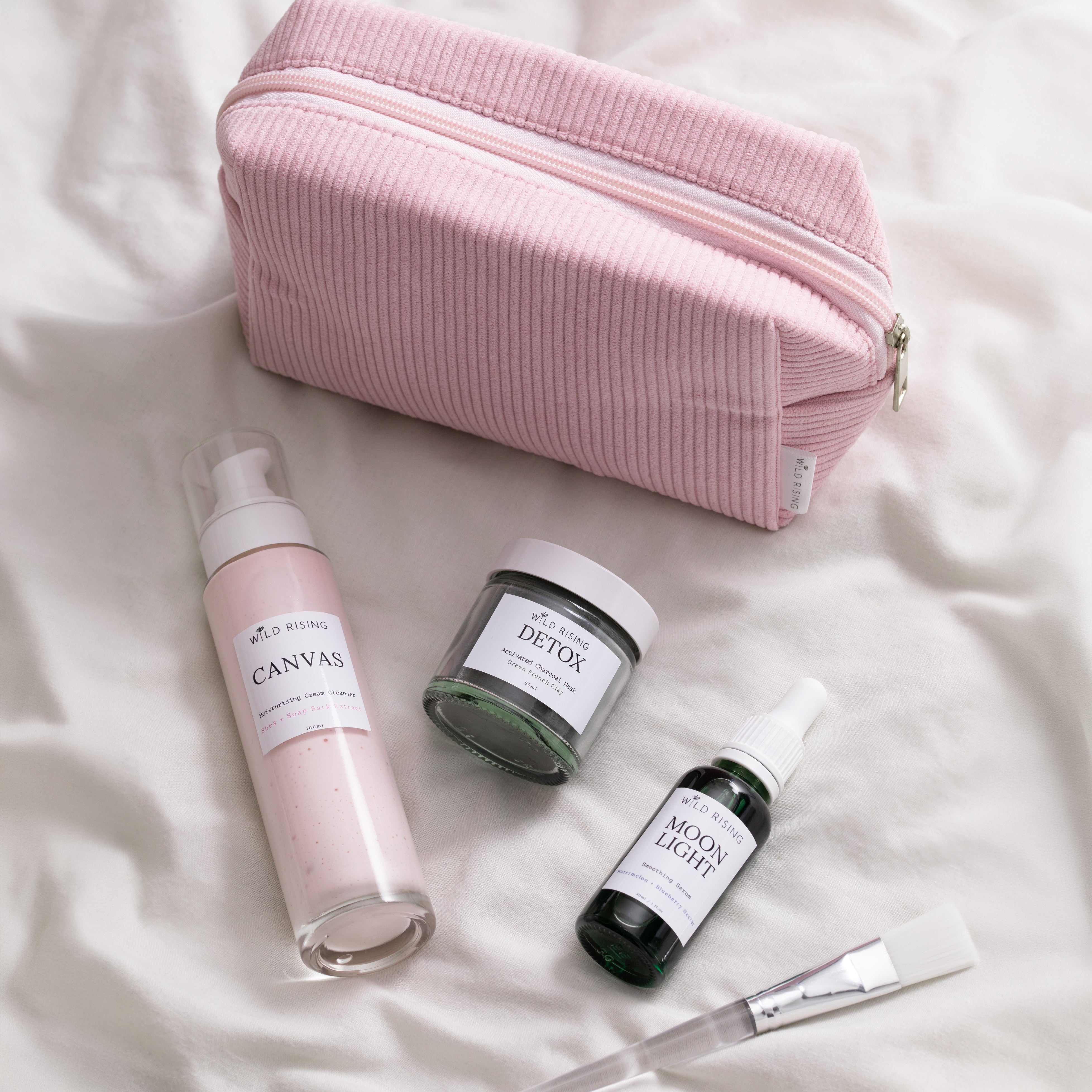 skincare products laid in front of a pink corded bag