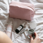 skincare products in front of a pink corded bag