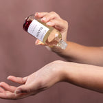 natural coconut and rose body and bath oil being poured onto skin